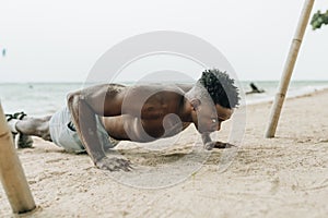 Portrait of a healthy young man doing push ups at the beach