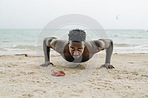 Portrait of a healthy young man doing push ups at the beach