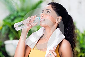 Portrait of healthy young woman drinking water during workout