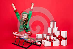 Portrait of her she nice attractive cheerful overjoyed pre-teen elf Santa Claus look sitting on sled lotus pose position