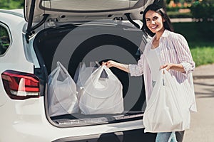 Portrait of her she nice-looking attractive careful cheerful lady putting bags buyings goods in truck pile stack supply photo