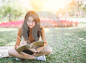 Portrait of high school girl lay down and read a book in park, education reading book and writing concept