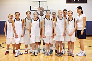 Portrait Of High School Sports Team In Gym With Coach