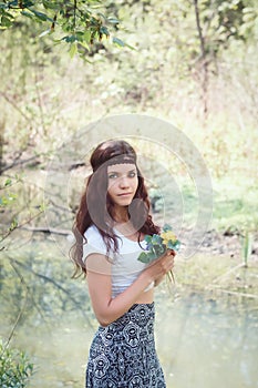 Portrait of hippie girl in forest with flowers