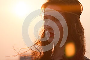 Portrait of a hippie woman with headband looking far away at sunset with windy hair.