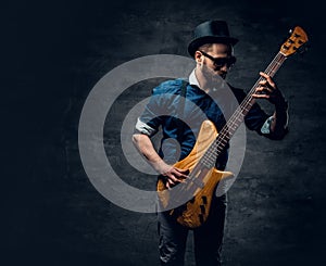 Portrait of the hipster bass player dressed in cylinder hat.