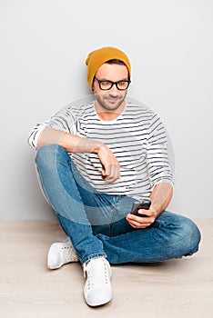 Portrait of hipster man in cap and glasses typing sms