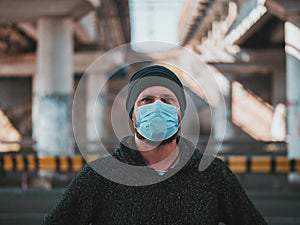 Portrait Of A Hipster Man In A Medical Mask For Protection Against Flu Virus Or Coronavirus Outdoor On The Background Of The