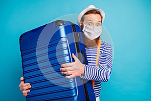 Portrait of his he amazed confused passenger bearded guy wearing safety gauze mask holding suitcase cov ncov-2 influenza