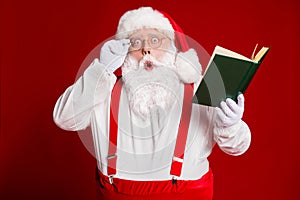 Portrait of his he attractive amazed stunned wondered fat white-haired Santa reading book education pout lips isolated