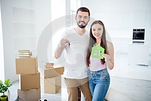 Portrait of his he her she nice attractive cheerful cheery couple embracing holding in hands key green house figure