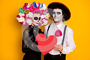 Portrait of his he her she nice glamorous cheery couple embracing holding in hands red paper card cupid amour calavera