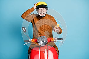Portrait of his he nice attractive cheerful cheery amazed wondered bearded grey-haired man riding moped using device