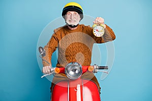 Portrait of his he nice attractive cheerful cheery confident bearded grey-haired man riding moped holding in hand