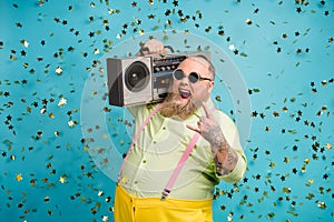 Portrait of his he nice attractive cheerful cheery funky cool crazy bearded guy carrying boombox showing horn sign