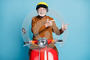 Portrait of his he nice attractive cheerful cheery glad bearded grey-haired man riding moped showing copy space advice