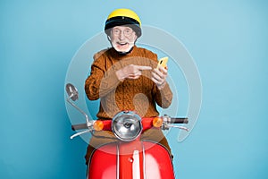 Portrait of his he nice attractive cheerful cheery glad bearded grey-haired man riding moped using demonstrating device