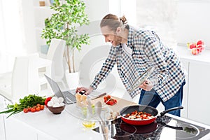 Portrait of his he nice attractive cheerful focused guy making fresh delicious dinner lunch snack salad checking recipe