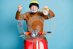 Portrait of his he nice attractive cheerful glad successful bearded grey-haired man courier riding moped holding in hand