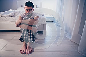 Portrait of his he nice attractive depressed guy sitting on floor suffering from insomnia bad unpleasant feelings at