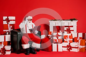 Portrait of his he nice attractive funky fat amazed astonished Santa using laptop sitting in armchair browsing reading e