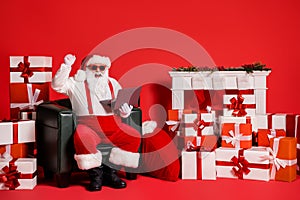 Portrait of his he nice attractive funky fat cheerful cheery lucky Santa using laptop sitting in armchair rejoicing shop
