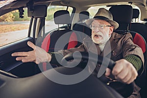 Portrait of his he nice experienced mad annoyed fury furious grey-haired man driving car in traffic jam holding steering