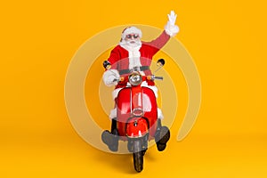 Portrait of his he nice funny playful childish cheerful cheery Santa riding motor bike having fun waving hello fooling