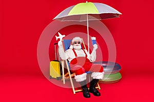 Portrait of his he nice handsome cheery bearded fat Santa tourist sitting in chair resting holding in hands air tickets