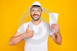 Portrait of his he nice-looking attractive cheerful cheery glad guy wearing white t-shirt holding in hand tickets