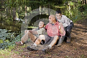 Portrait Hispanic father and sons outdoors by pond photo