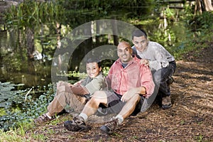 Portrait Hispanic father and sons outdoors by pond