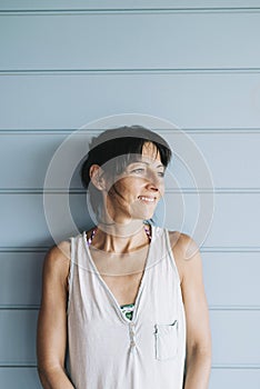 Portrait of hispanic woman with summer dress and ponytail while leaning on wood wall