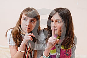 Portrait of holding fingers on lips in silence 2 beautiful girlfriends having fun together looking at camera on light background