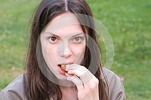 Portrait of a homeless woman eating a sandwich with bread and sausage.