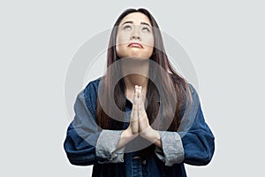 Portrait of hopeful prayer beautiful brunette asian young woman in casual blue denim jacket with makeup standing with palm hands