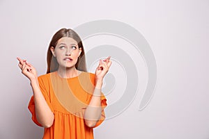 Portrait of hopeful young woman with crossed fingers