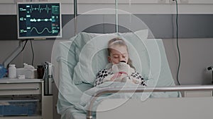 Portrait of hospitalized sick child falling asleep while holding teddy bear in hands