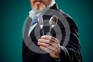 A portrait of hungry man in suit holding spoon and fork