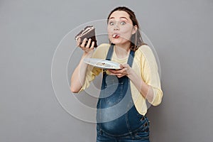 Portrait of a hungry pregnant woman eating sweet chocolate cake