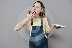 Portrait of a hungry pretty pregnant woman eating chocolate cake