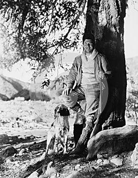 Portrait of hunter and dog under tree