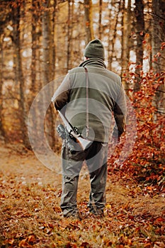 Portrait of hunter or ranger with gun or rifle in the forest looking out or hunting of some venison, hunting period