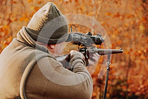 Portrait of hunter or ranger with gun or rifle in the forest looking out or hunting of some venison, hunting period