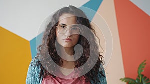 Portrait if serious and sad girl looking at camera on colorful background indoors