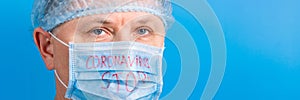 Portrait of ill man in medical unifrom and protective mask with stop text at blue background. Respiratory protection.