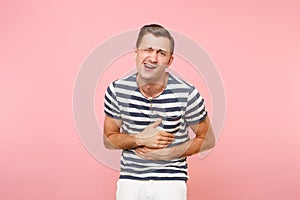 Portrait of ill painful young man in striped t-shirt put his hands on stomach with stomachache or gastroenterologists