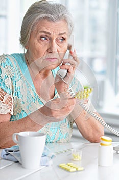 Portrait of ill senior woman calling doctor