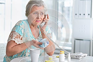 Portrait of ill senior woman calling doctor