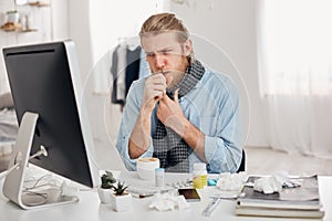Portrait of ill sick bearded male manager coughs, has cold and flu. Young fair-haired man has running nose, cough and